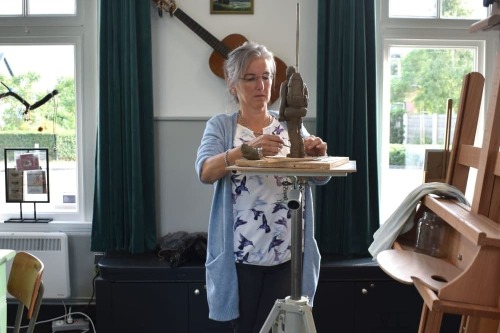 Marieke bezig met het maken van een beeld van een reiziger, voor op de schouw in de wachtruimte van Station Krabbendijke